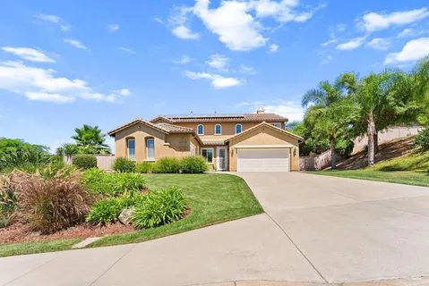 a front view of a house with a yard and potted plants