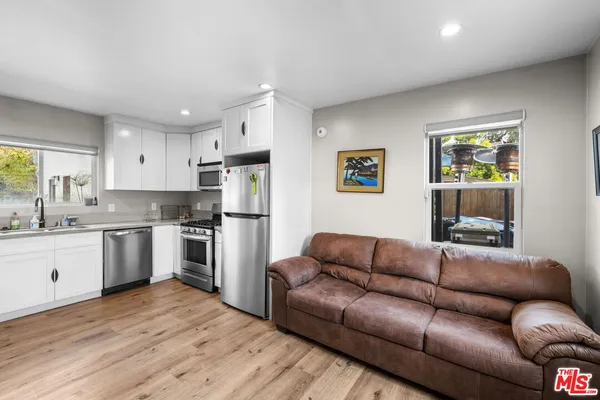 a living room with stainless steel appliances furniture and a kitchen view