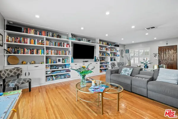 a living room with furniture a flat screen tv and a book shelf