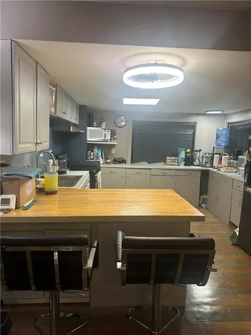 a room with stainless steel appliances kitchen island granite countertop a table chairs and a refrigerator