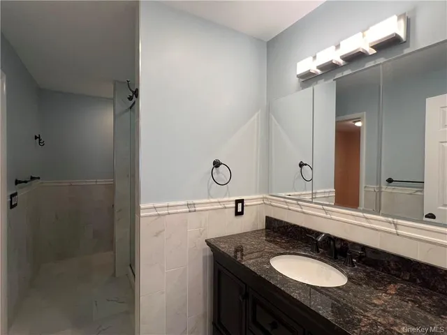 a bathroom with a granite countertop sink a large mirror and a shower