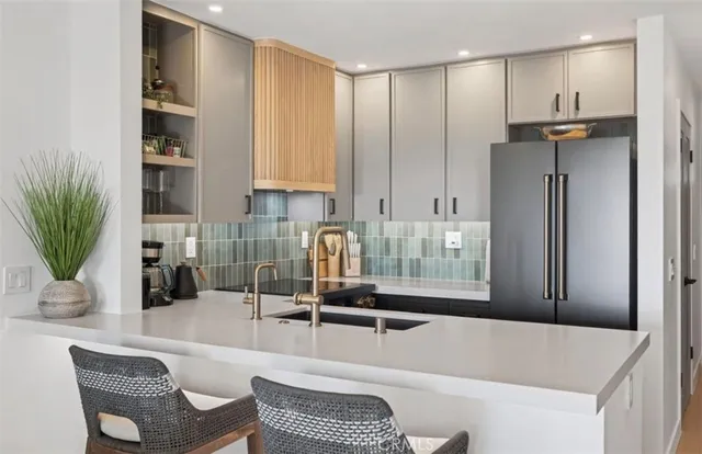 a kitchen with granite countertop a refrigerator a stove a sink and white cabinets with wooden floor