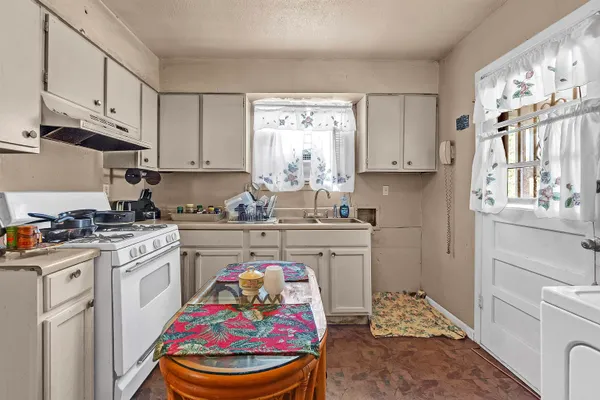 a kitchen with stainless steel appliances a stove a sink cabinets and a window