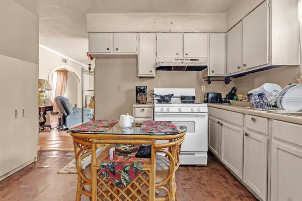 a kitchen with stainless steel appliances granite countertop a sink a stove a dining table and chairs