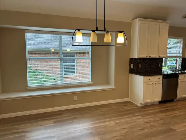a view of an empty room with a kitchen and wooden floor