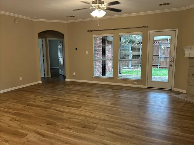 a view of an empty room with window and wooden floor
