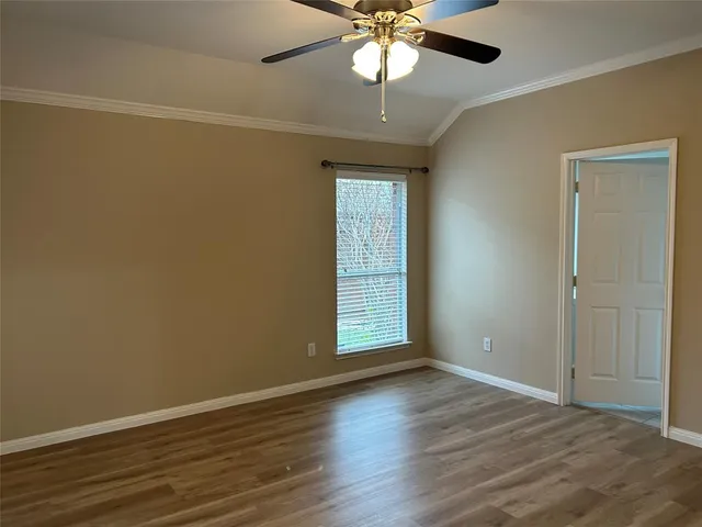 an empty room with wooden floor chandelier fan and windows