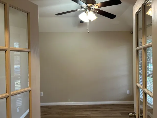 a view of an empty room with a window and wooden floor