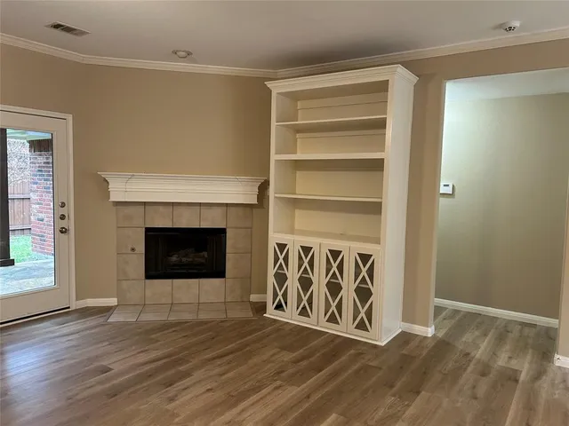 a view of an empty room with wooden floor a fireplace and a window