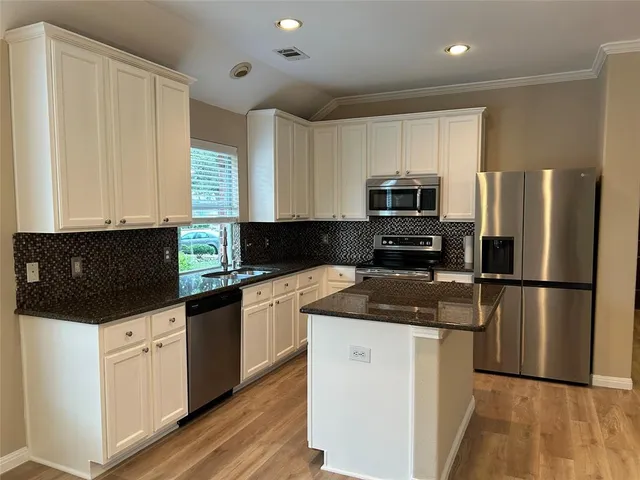 a kitchen with granite countertop a refrigerator a sink a stove a microwave and wooden cabinets