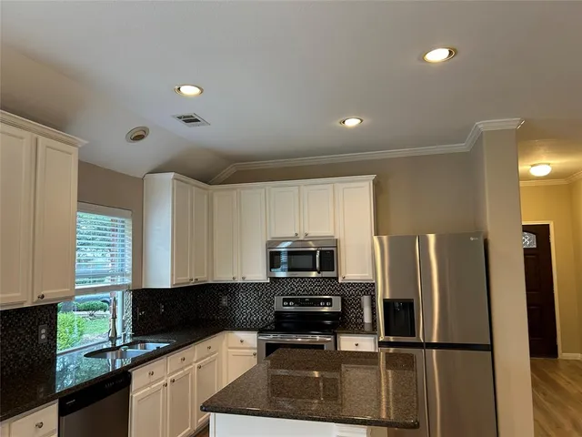 a kitchen with granite countertop a refrigerator and a stove top oven