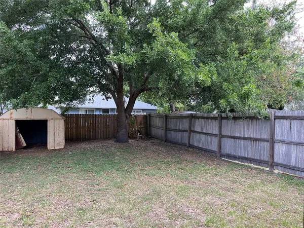 a view of backyard with wooden fence and a large tree