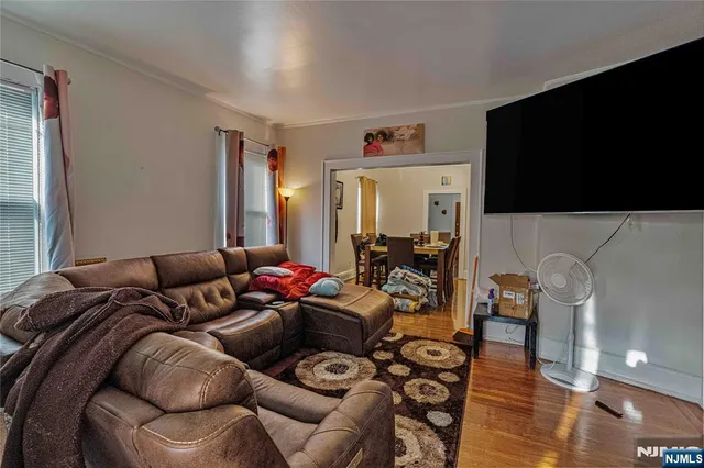 a living room with furniture a flat screen tv and wooden floor