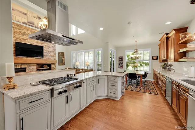 a kitchen with stainless steel appliances kitchen island granite countertop a stove top oven a sink a dining table and chairs