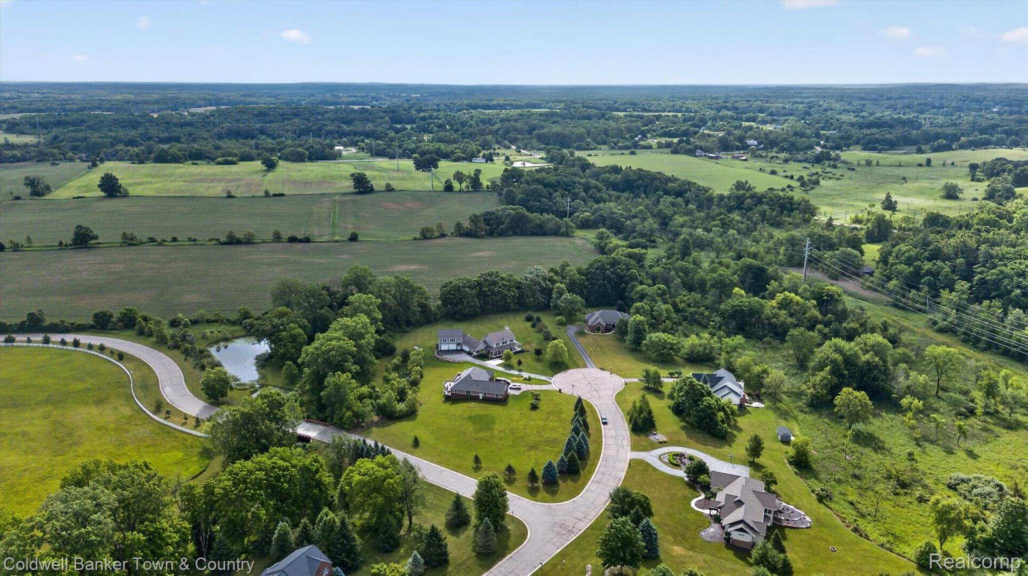 918 Gray Fox Court Howell, MI 48843 - Photo 77 of 84 Expansive aerial view showcasing verdant landscapes, established residential properties, a winding paved road, a serene pond, and abundant mature trees