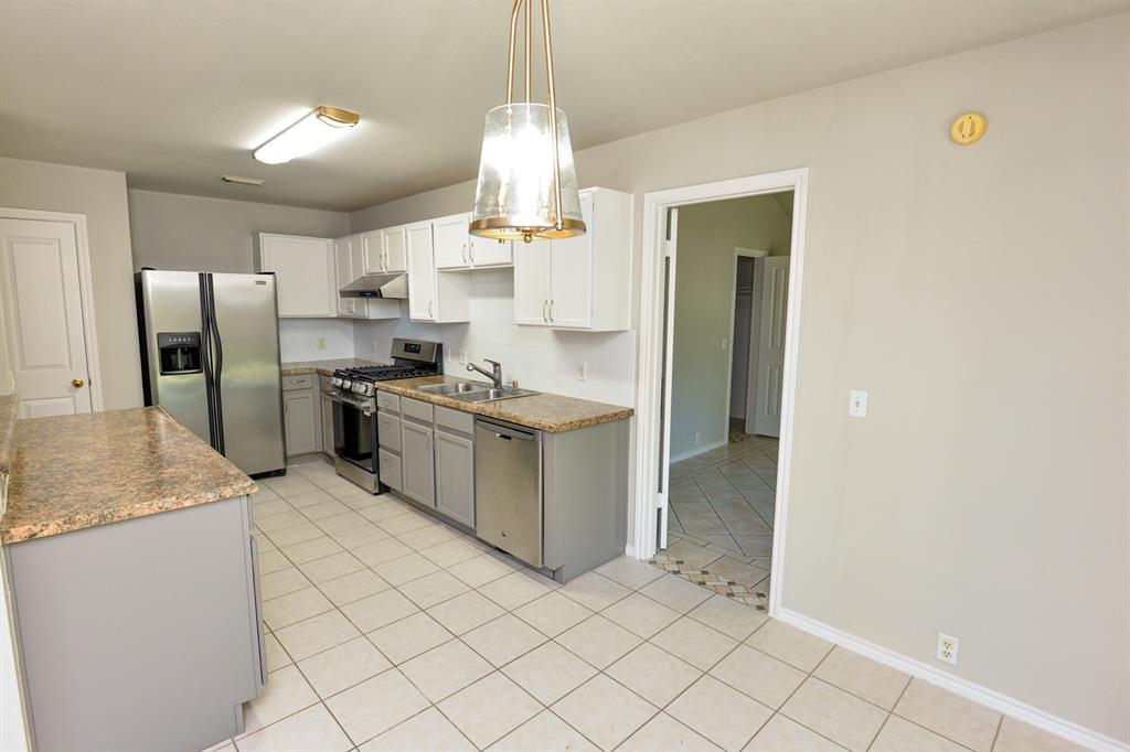 2109 Kimra Lane Cedar Park, TX 78613 - Photo 12 of 31 Kitchen featuring stainless steel appliances, white cabinets, pendant lighting, light tile patterned floors, and under cabinet range hood