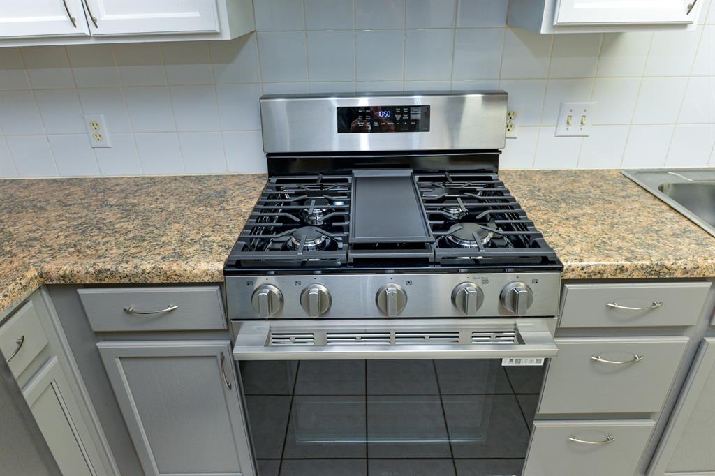2109 Kimra Lane Cedar Park, TX 78613 - Photo 13 of 31 Kitchen featuring gas range, gray cabinets, decorative backsplash, and light stone counters