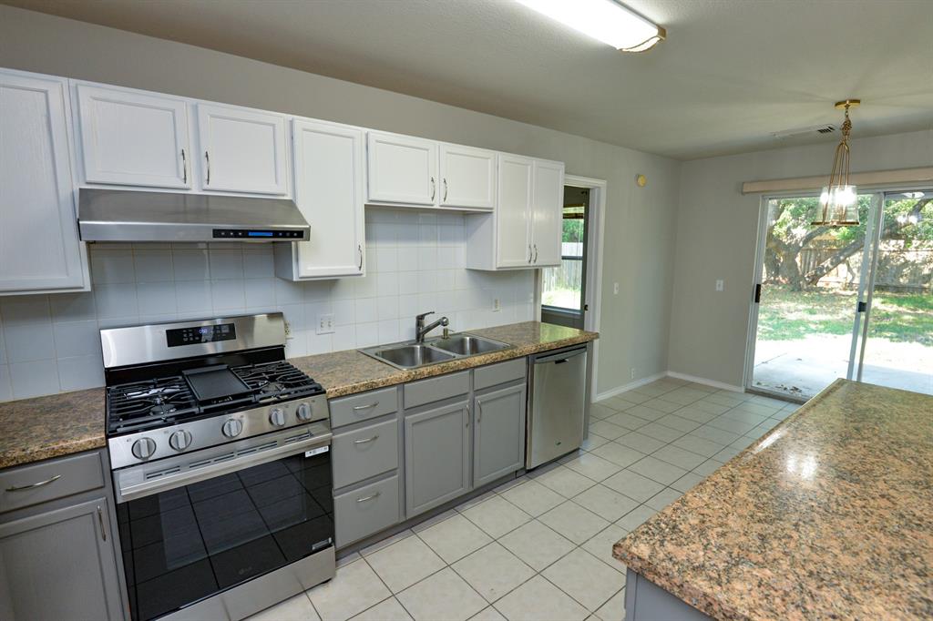 2109 Kimra Lane Cedar Park, TX 78613 - Photo 14 of 31 Kitchen featuring stainless steel appliances, gray cabinetry, light tile patterned floors, tasteful backsplash, and under cabinet range hood