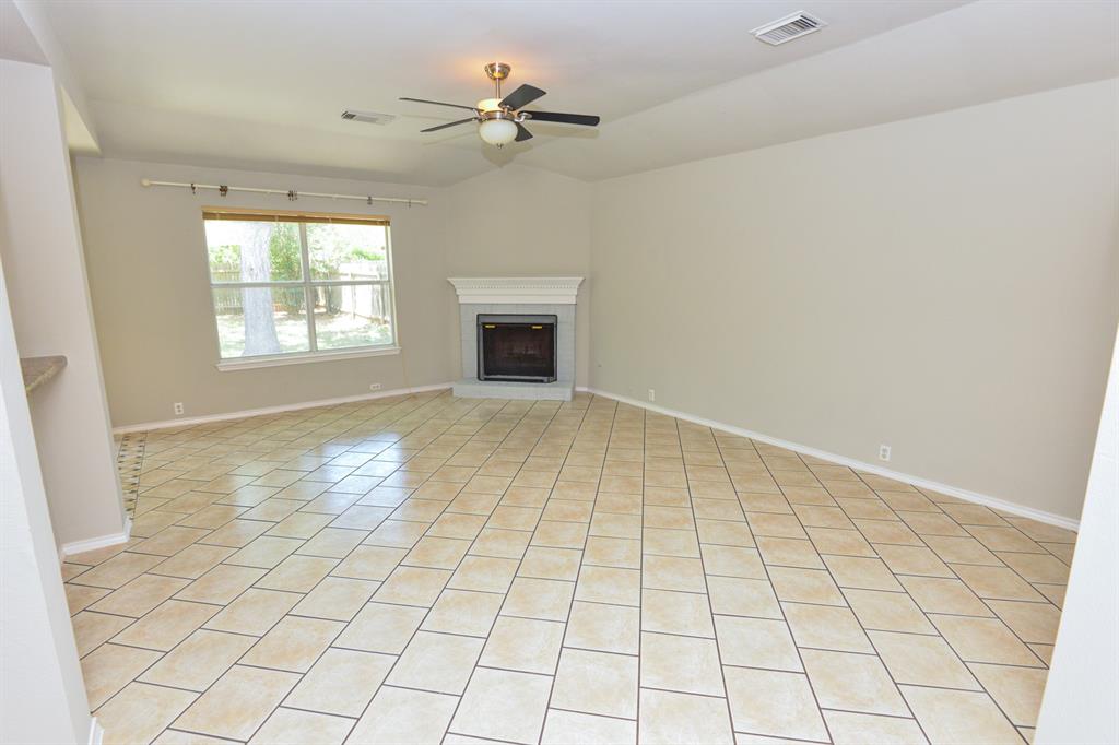 2109 Kimra Lane Cedar Park, TX 78613 - Photo 7 of 31 Unfurnished living room with a fireplace with raised hearth, light tile patterned flooring, and ceiling fan