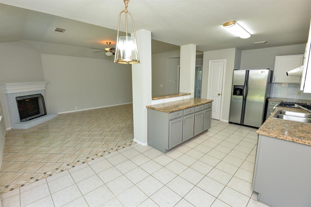 2109 Kimra Lane Cedar Park, TX 78613 - Photo 8 of 31 Kitchen with decorative light fixtures, stainless steel fridge with ice dispenser, gray cabinetry, light tile patterned floors, and light stone counters