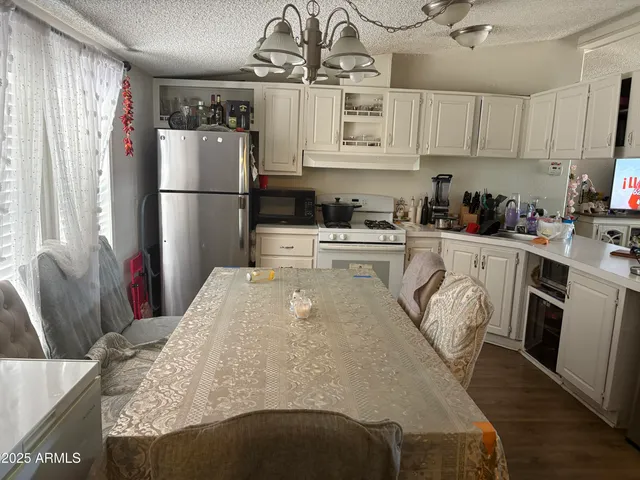 a kitchen with stainless steel appliances granite countertop a refrigerator a stove a sink dishwasher and white cabinets with wooden floor