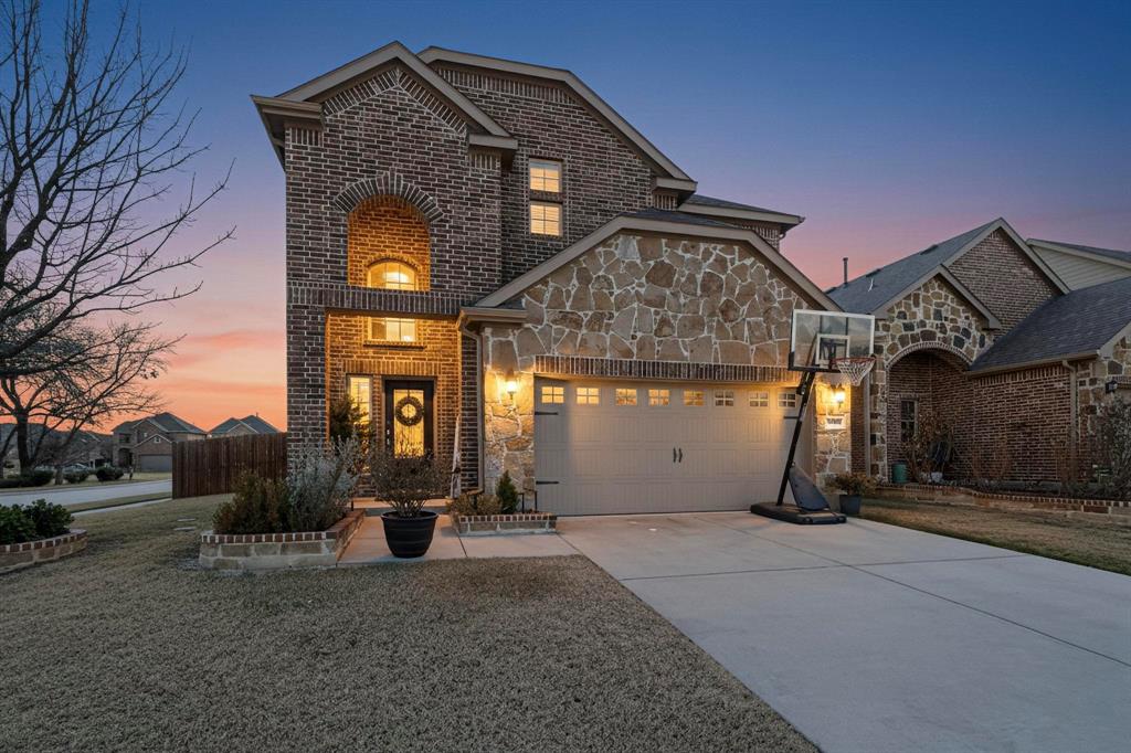 French provincial home with brick siding, concrete driveway, stone siding, and an attached garage