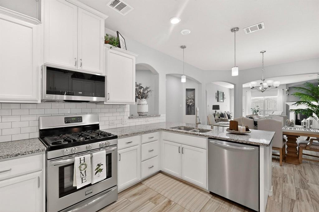 9801 Diamondback McKinney, TX 75071 - Photo 39 of 40 Kitchen with stainless steel appliances, white cabinetry, a peninsula, open floor plan, and decorative backsplash