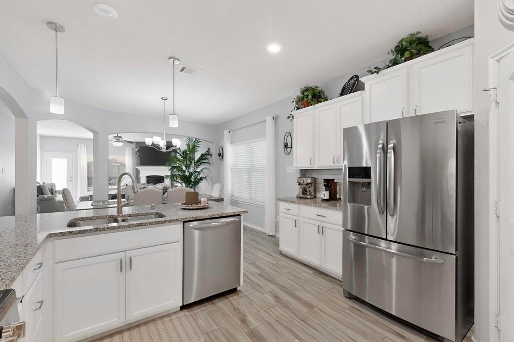 9801 Diamondback McKinney, TX 75071 - Photo 40 of 40 Kitchen with stainless steel appliances, white cabinets, open floor plan, and light stone countertops