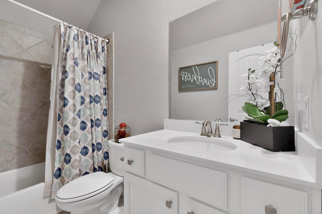 9801 Diamondback McKinney, TX 75071 - Photo 14 of 40 Bathroom with a textured wall, shower / bathtub combination with curtain, and vanity