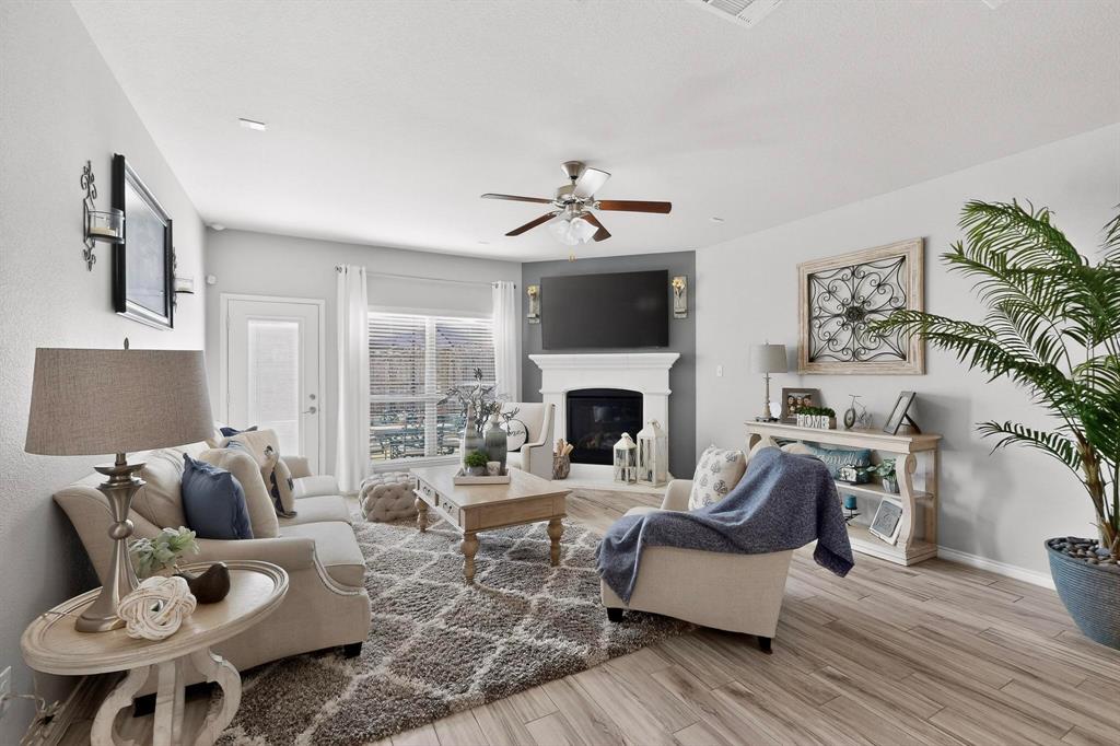 9801 Diamondback McKinney, TX 75071 - Photo 4 of 40 Living area with light wood-type flooring, a ceiling fan, and a glass covered fireplace