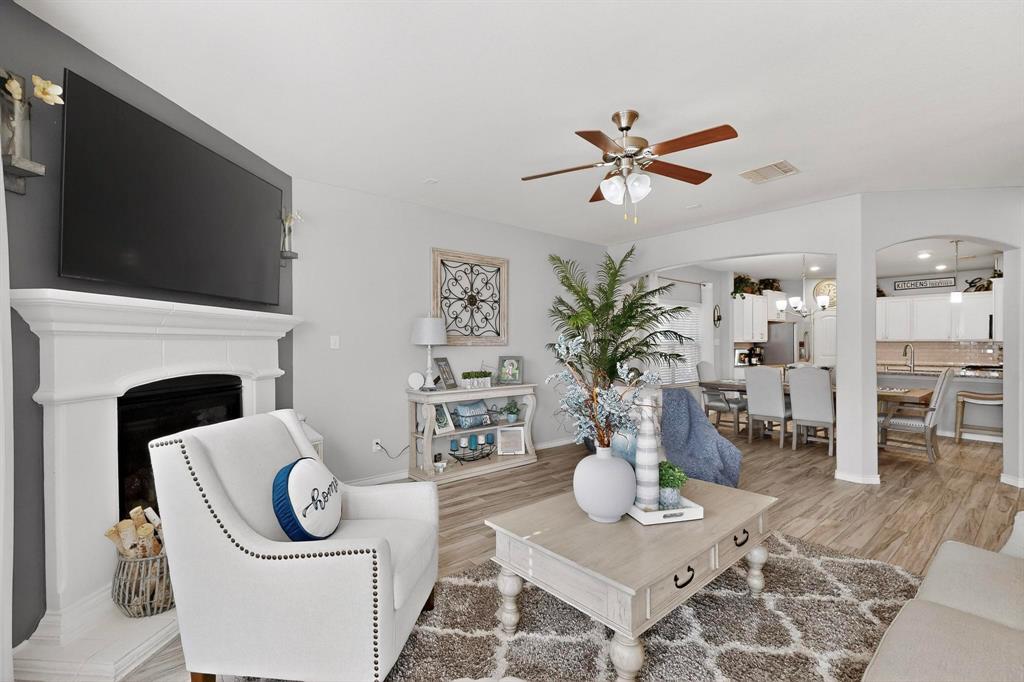 9801 Diamondback McKinney, TX 75071 - Photo 6 of 40 Living area featuring arched walkways, a ceiling fan, light wood-type flooring, and a fireplace