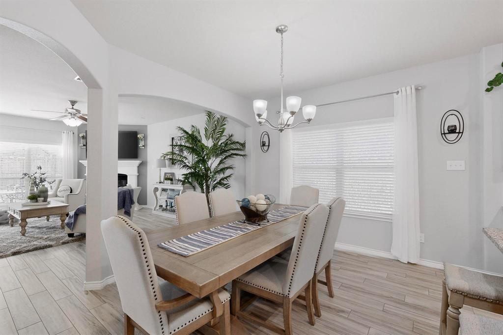 9801 Diamondback McKinney, TX 75071 - Photo 8 of 40 Dining area with wood finish floors, arched walkways, a ceiling fan, a fireplace, and hanging lights
