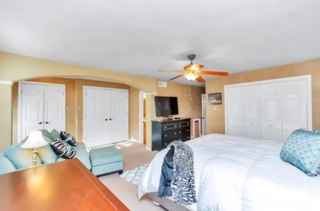 a spacious bedroom with a bed a couch and a flat screen tv