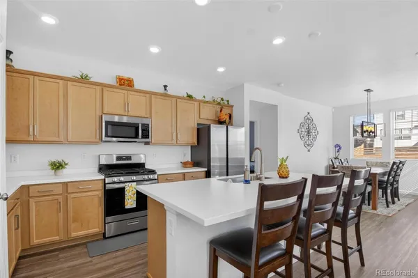 a kitchen with stainless steel appliances a stove a sink a microwave a refrigerator white cabinets and wooden floor
