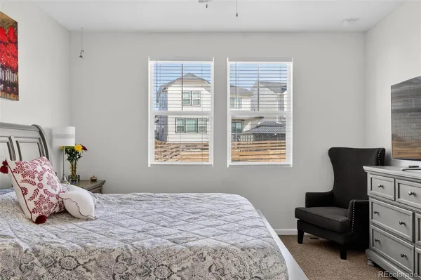 a bedroom with a bed chair and two windows