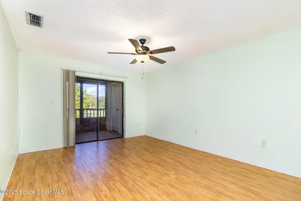 a view of a room with wooden floor and a ceiling fan