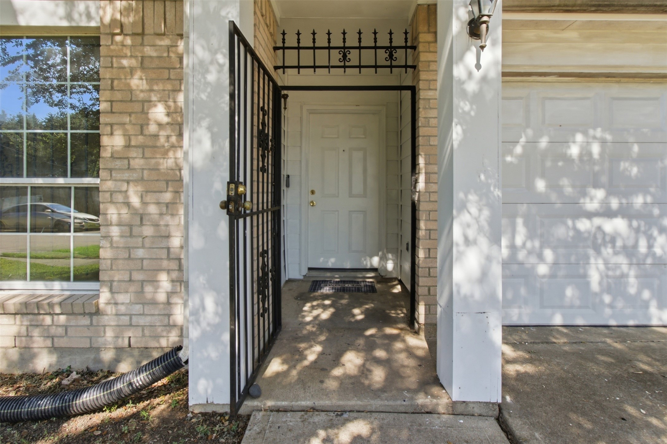 Charming entryway with a secure wrought iron gate, inviting front door, and elegant exterior lighting.
