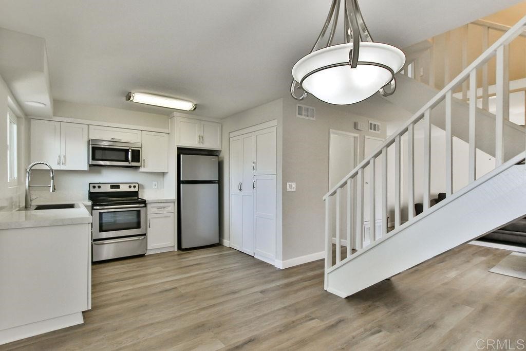 10022 Great Rock Road Santee, CA 92071 - Photo 12 of 32 a kitchen with stainless steel appliances granite countertop a refrigerator a stove oven a sink dishwasher and white cabinets with wooden floor