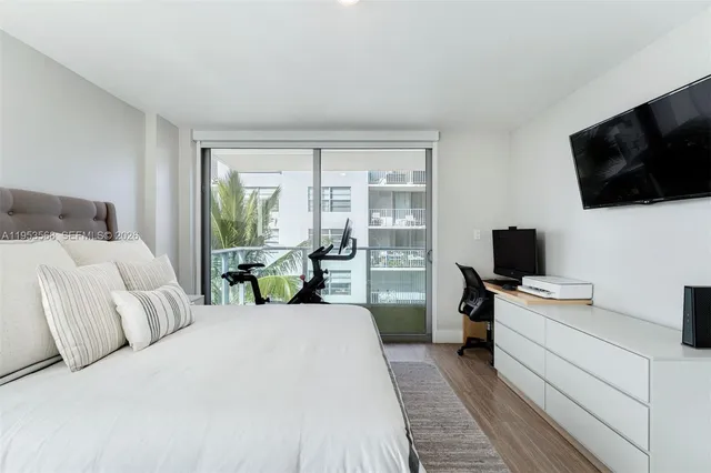 a bedroom with a bed and a flat tv screen on the dresser