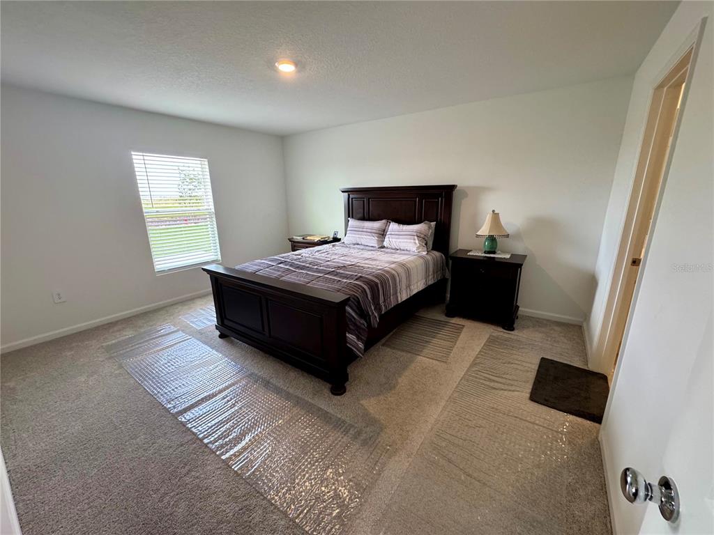 2405 Bluestone Road Haines City, FL 33844 - Photo 9 of 18 a spacious bedroom with a bed and wooden floor