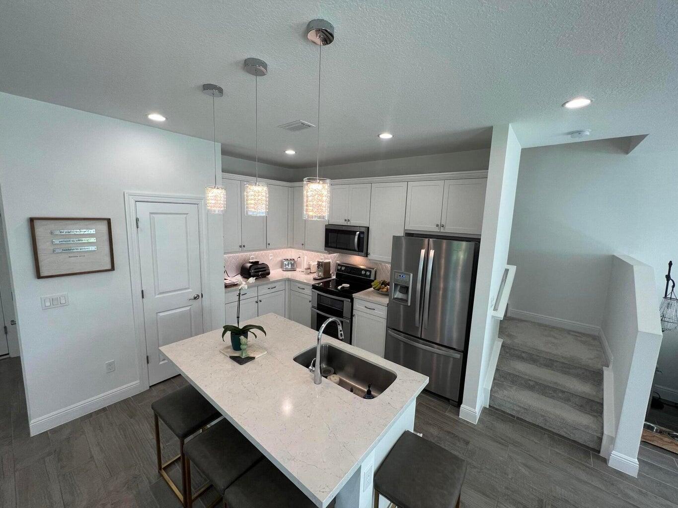 562 Parsons Way Deerfield Beach, FL 33442 - Photo 4 of 15 a kitchen with stainless steel appliances a refrigerator a sink dishwasher a stove and white cabinets with wooden floor