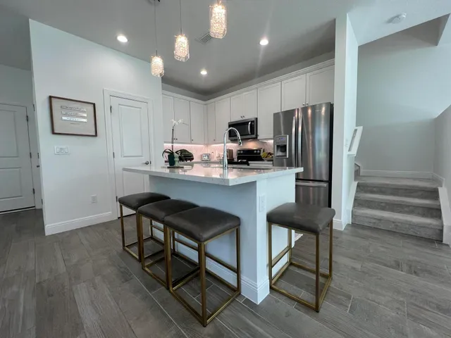 a kitchen with stainless steel appliances a dining table chairs refrigerator and cabinets