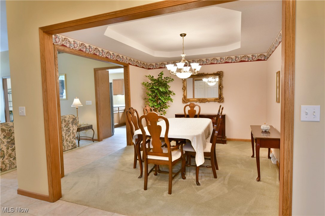 1997 East County Line Road Mineral Ridge, OH 44440 - Photo 5 of 35 Dining area with an inviting chandelier, a healthy amount of sunlight, light tile patterned floors, and a raised ceiling