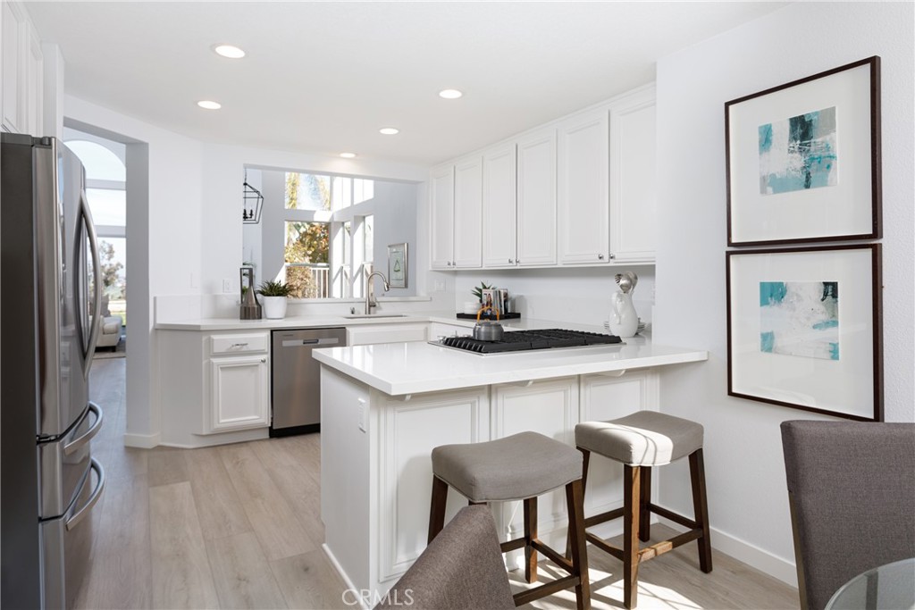 29672 Teracina Laguna Niguel, CA 92677 - Photo 11 of 35 a kitchen with a refrigerator a sink dishwasher and white cabinets with wooden floor
