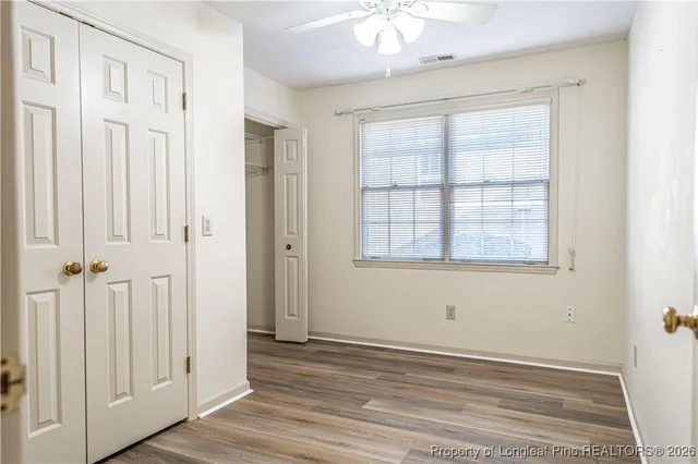 an empty room with wooden floor cabinet and windows