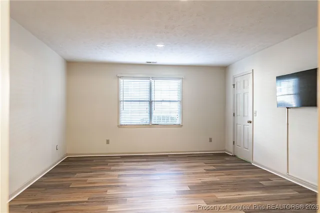 an empty room with wooden floor cabinet and windows