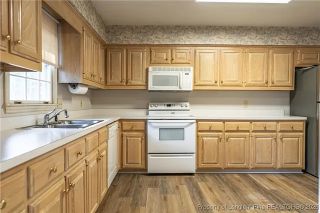 a kitchen with granite countertop a sink cabinets stainless steel appliances and a window