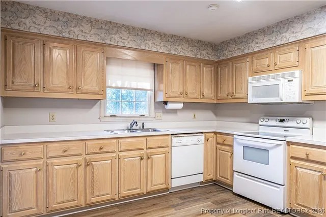 a kitchen with white cabinets white appliances and sink