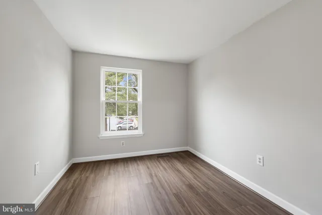 an empty room with wooden floor and window