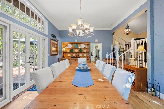 a view of a dining room with furniture a chandelier and large windows